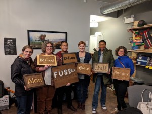 a group of people are smiling and holding signs they made with a laser cutter at fuse 33 makerspace in calgary