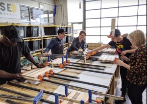 a group of people are using clamps to hold the cutting boards they made at fuse 33 makerspace in calgary