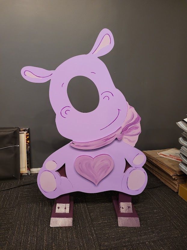 A photo opportunity cutout of a purple rhino with a heart on its chest.