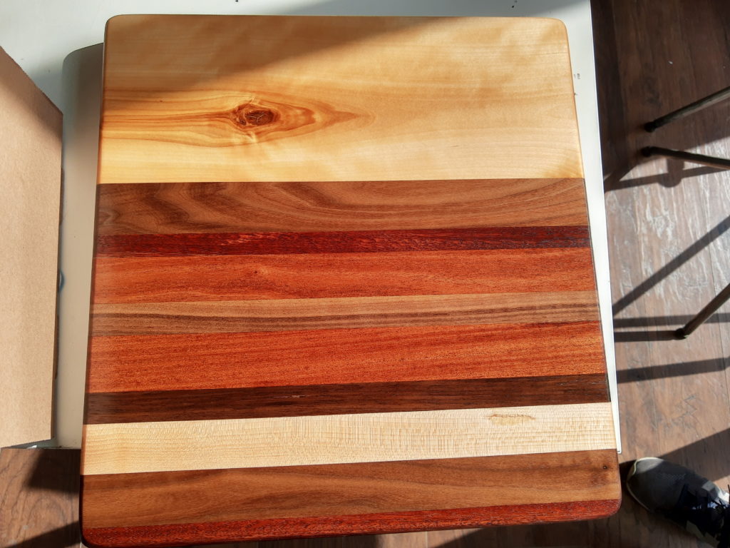 wood striped cutting board in different colors of wood light dark and red toned. Created at Fuse 33 makerspace in a workshop