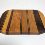 a wood cutting board made with joinery in different colors of wood in stripes.