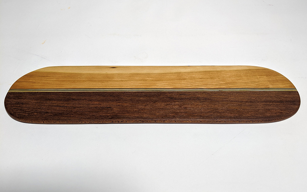 a wood cutting board made with joinery in different colors of wood in stripes.