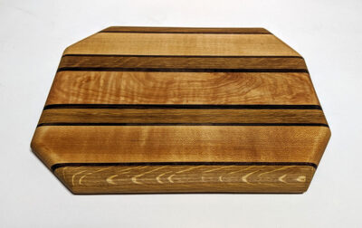 a wood cutting board made with joinery in different colors of wood in stripes.
