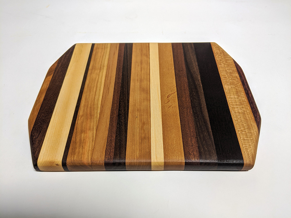 a wood cutting board made with joinery in different colors of wood in stripes.