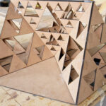 a small scale wooden model of the Freezer burn effigy. A series of triangles stack in an artistic pattern