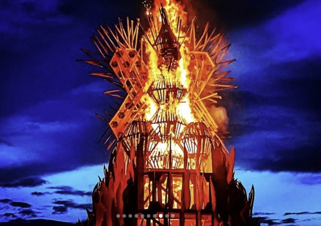 a photo taken at night of a wooden sculpture 'the Temple' on fire at the Freezer Burn festival